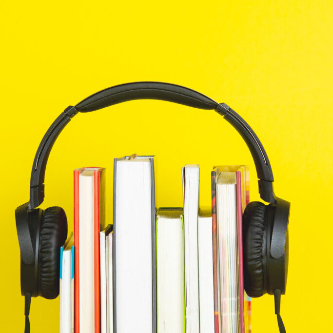 concept of audio book. headphone and books on yellow background