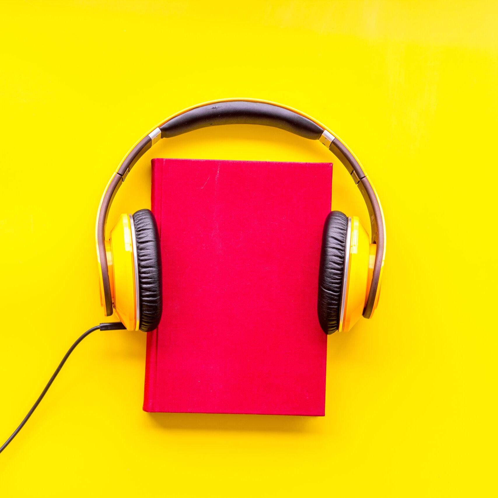 listen to audio books with headphone on yellow library desk background flatlay